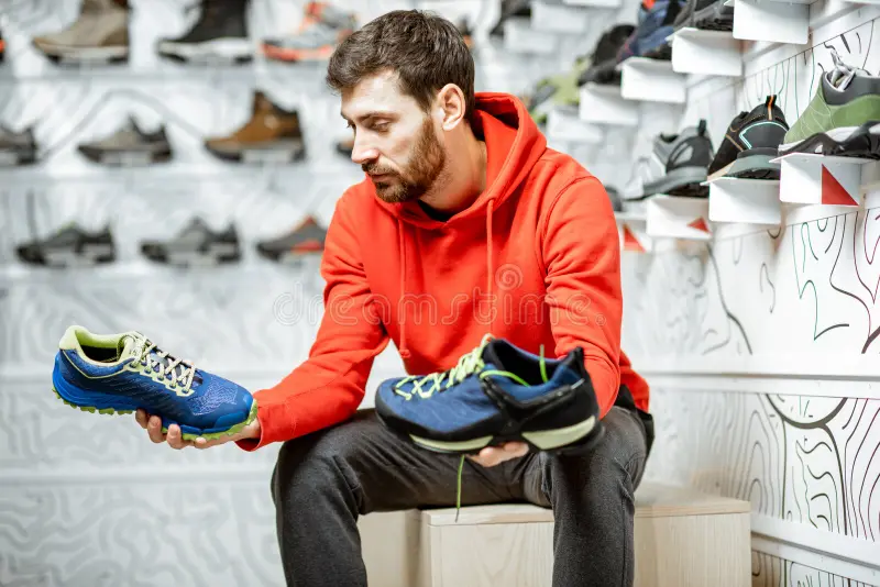 man-choosing-hiking-shoes-shop-trail-sitting-fitting-room-modern-sports-136782386